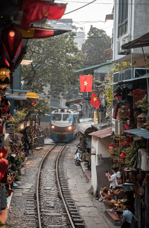 This is a photo of Hanoi Train Street with a train coming through